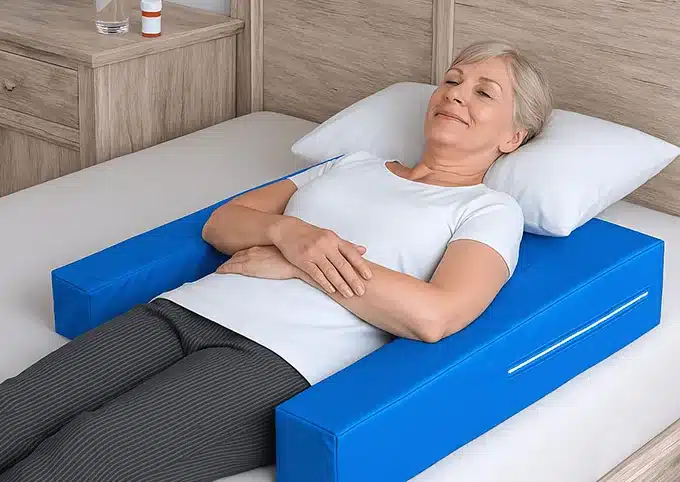 Woman in shoulder sling suffering from pain and poor sleep in recliner after surgery - the common problem the Restore You sleep restoration pillow solves by providing comfortable recovery in your own bed