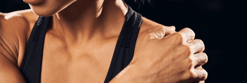Woman holding painful shoulder showing symptoms associated with the most common causes of shoulder pain.