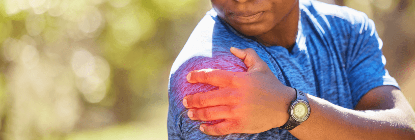 Person in blue athletic shirt holding their shoulder in pain, illustrating common shoulder arthritis symptoms including joint discomfort, stiffness, and limited mobility that patients experience with osteoarthritis, rheumatoid arthritis, or post-traumatic shoulder conditions requiring orthopedic evaluation and treatment.