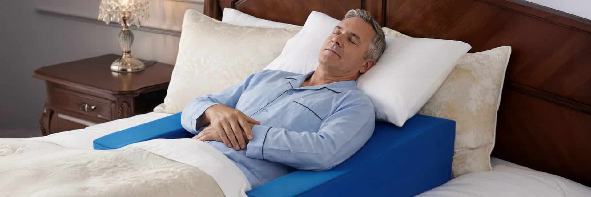 Man sleeping comfortably on wedge pillow for shoulder surgery with proper elevation and arm support in bedroom